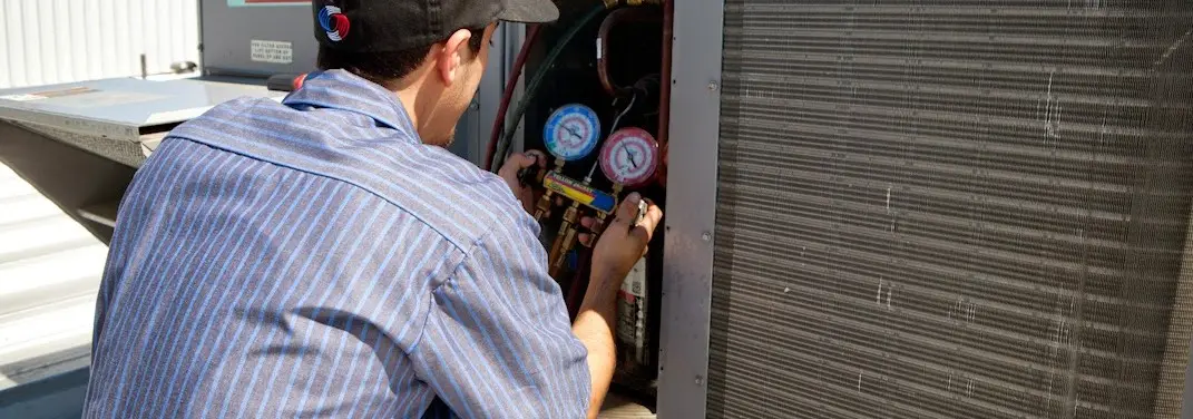HVAC technician servicing a condenser unit in Iowa Park